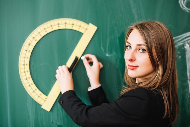 Free photo young woman drawing on blackboard