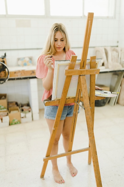 Free photo young woman drawing on easel at workshop