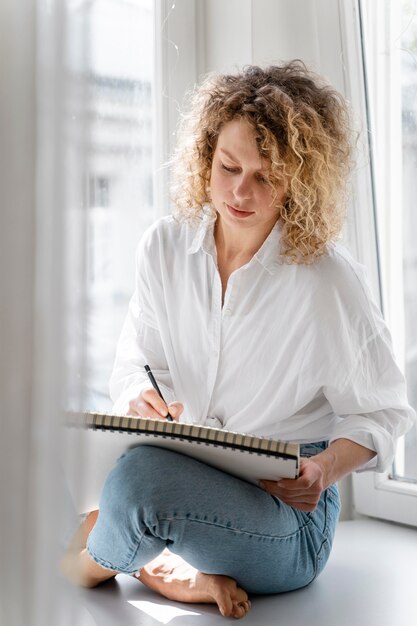 Young woman drawing at home near the window