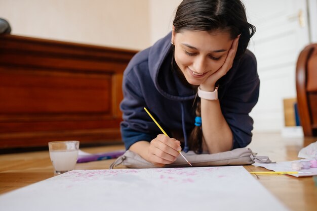 Young woman drawing laying on the floor at home