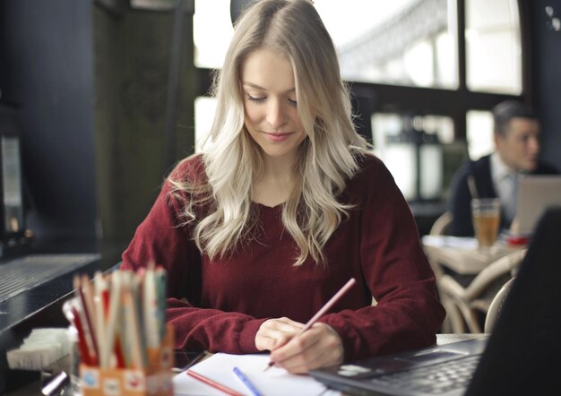 young woman draws on paper in a cafe