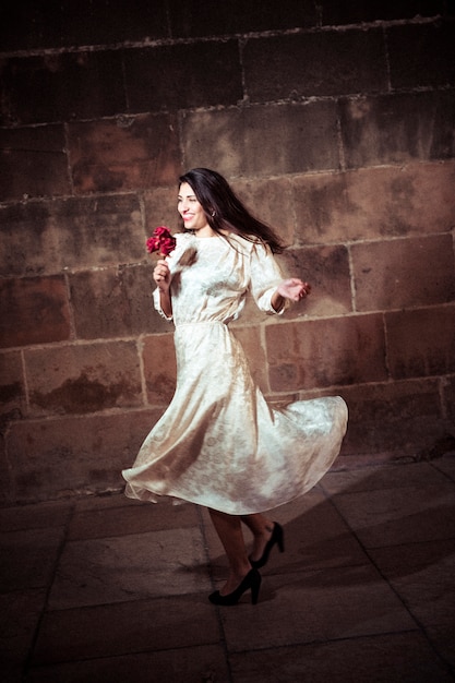 Free photo young woman in dress dancing in street