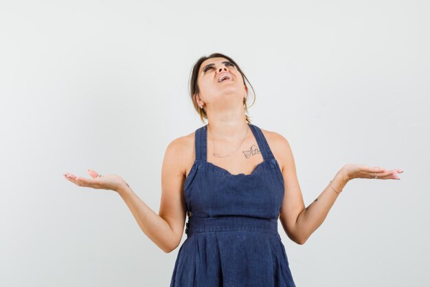 Young woman in dress looking up, spreading arms and looking happy