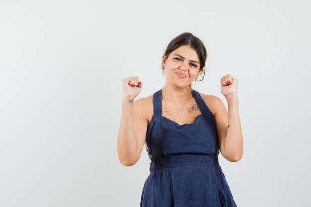 Young woman in dress showing winner gesture and looking lucky