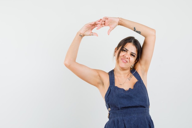 Free photo young woman in dress stretching arms over head and looking elegant