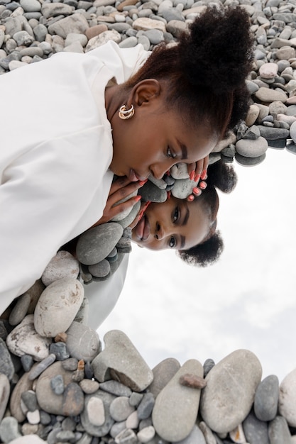 Free photo young woman dressed in white posing with mirror in rocks