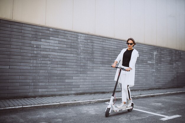 Young woman dressed in white riding scooter
