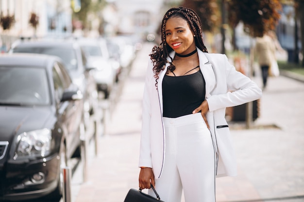 Young woman dressed in white suit outside the street