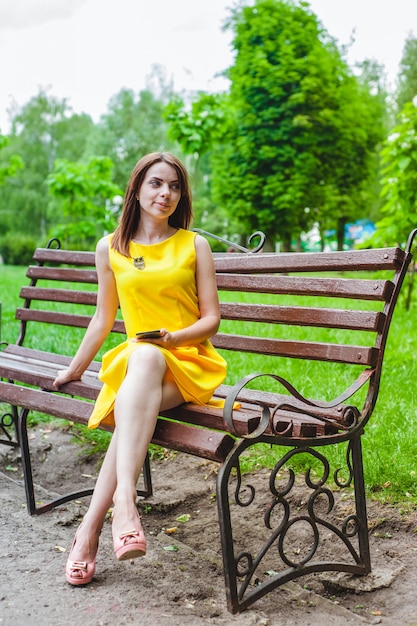 Free photo young woman dressed in yellow with a smart phone in her hand