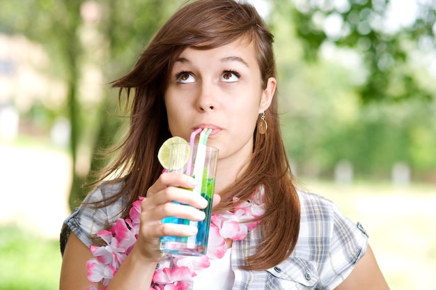 青いキュラソーカクテルを飲む若い女性
