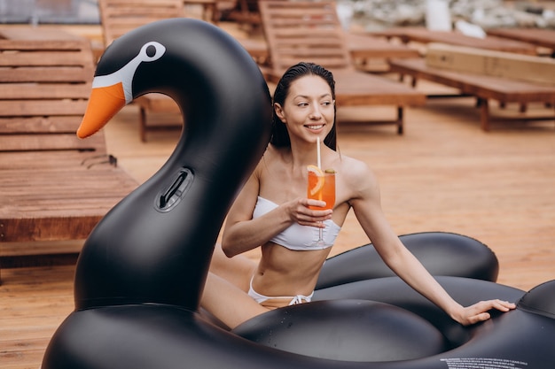 Giovane donna che beve cocktail a bordo piscina