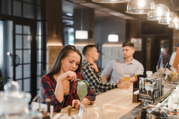 Young woman drinking cocktail drink at bar