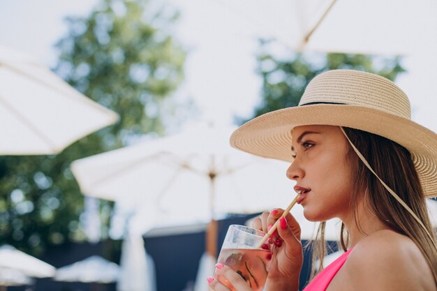 Young woman drinking coctail and lying on sunbed