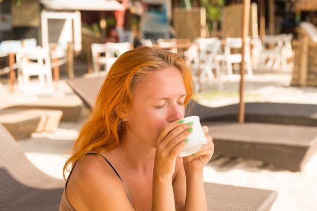 해변에서 커피를 마시는 젊은 여자