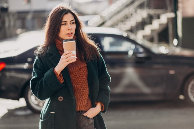 그녀의 차에 의해 커피를 마시는 젊은 여자