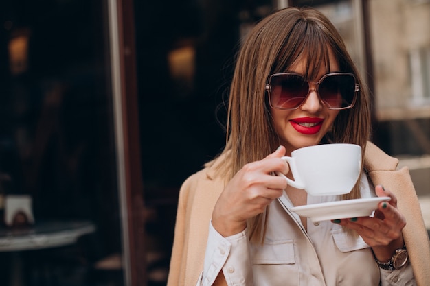 テラスのカフェでコーヒーを飲む若い女性