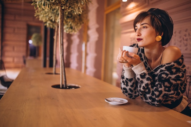 Giovane donna che beve il caffè in un caffè