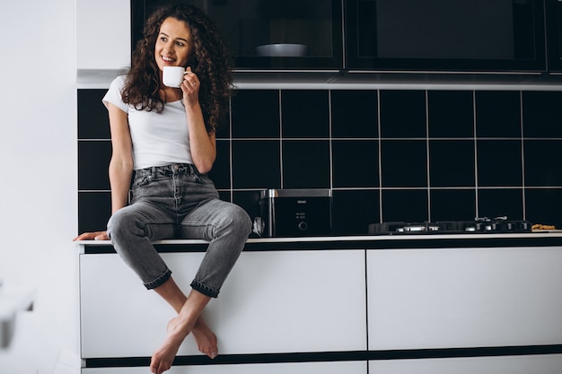 Молодая женщина пьет кофе на кухне