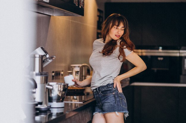 Young woman drinking coffee in the morning at the kitchen