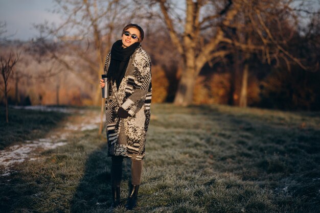 Young woman drinking coffee in the morning and walking in park