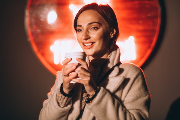 Young woman drinking coffee at night street