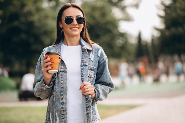 Giovane donna che beve caffè nel parco