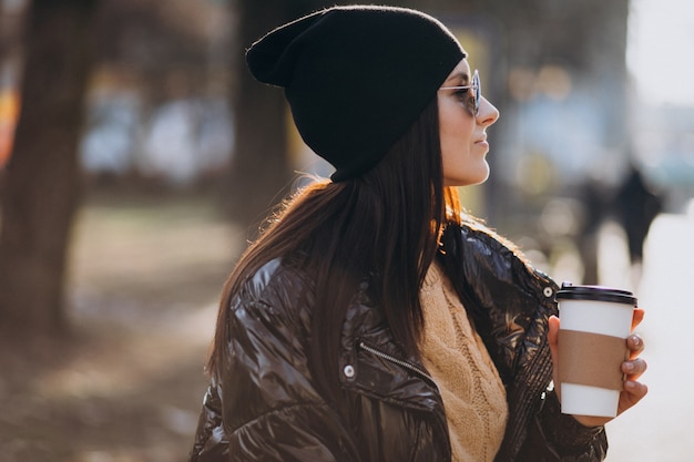 公園でコーヒーを飲む若い女性