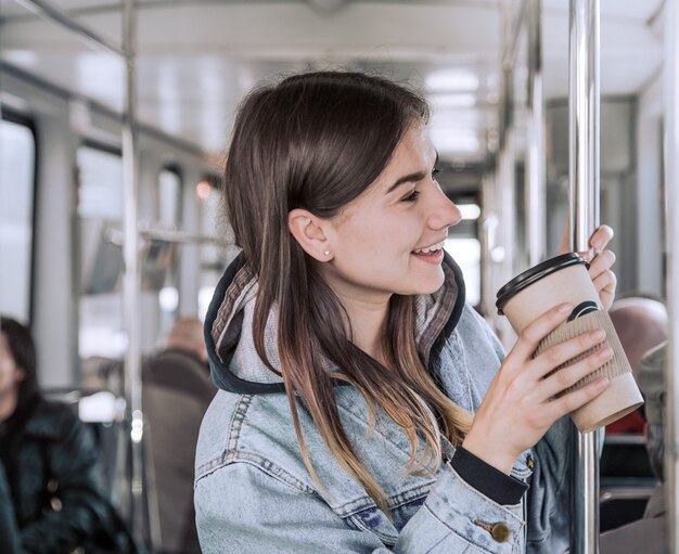 Young woman drinking coffee on public transport