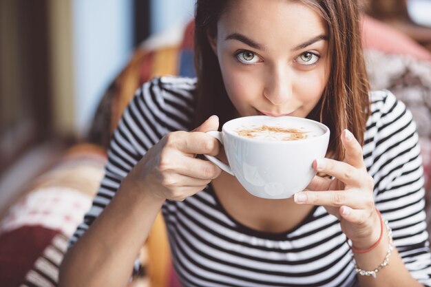 都市のカフェでコーヒーを飲む若い女性