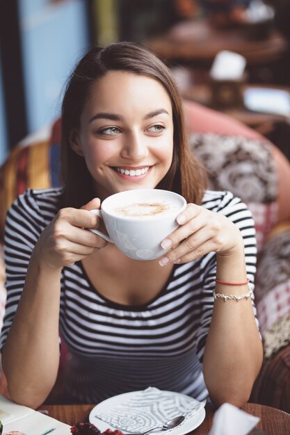 都市のカフェでコーヒーを飲む若い女性