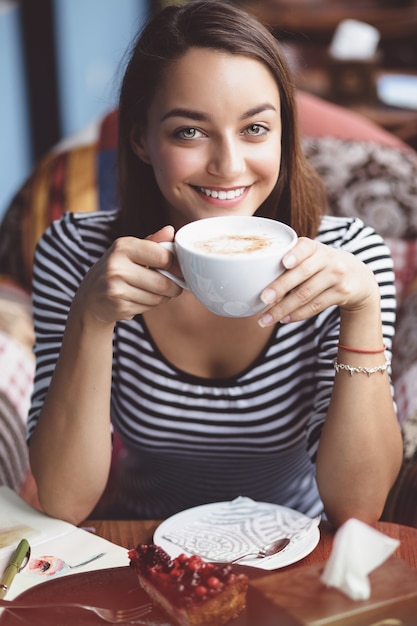 都市のカフェでコーヒーを飲む若い女性