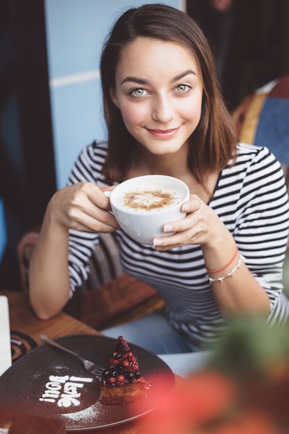 都市のカフェでコーヒーを飲む若い女性