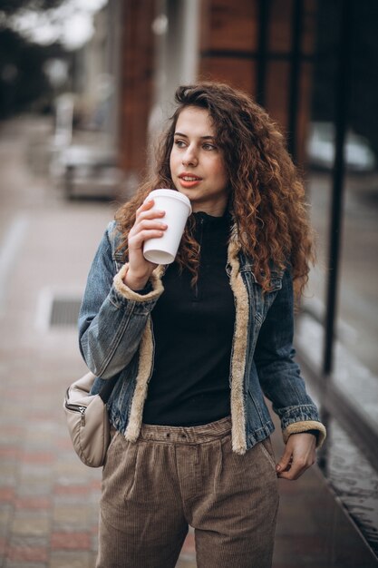 コーヒーを飲みながら携帯電話を使用して若い女性