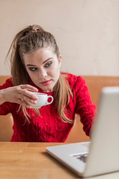 仕事をしながら若い女性がコーヒーを飲みます