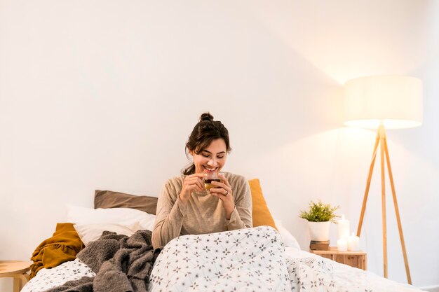 Young woman drinking her tea in bed