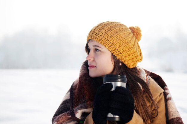 Young woman drinking hot drink outdoors
