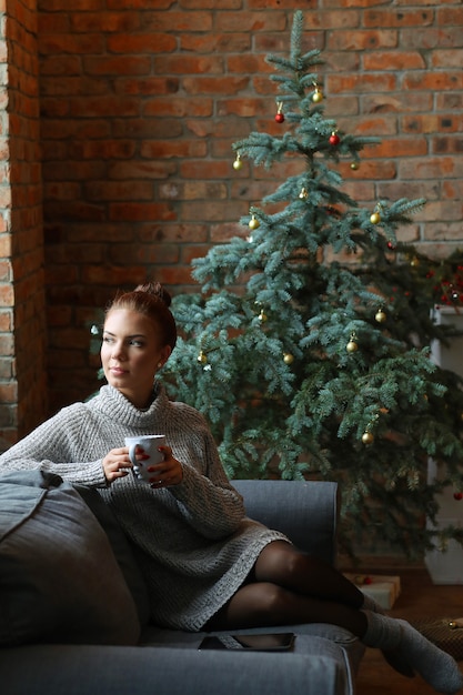 Young woman drinking hot tea on the sofa