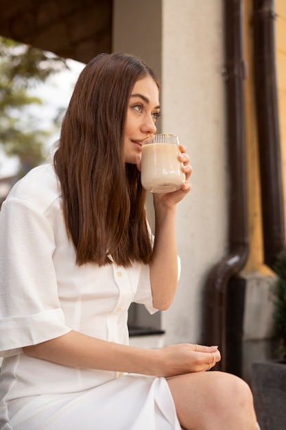 Free photo young woman drinking iced coffee