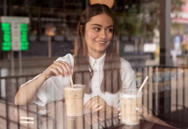 Free photo young woman drinking iced coffee