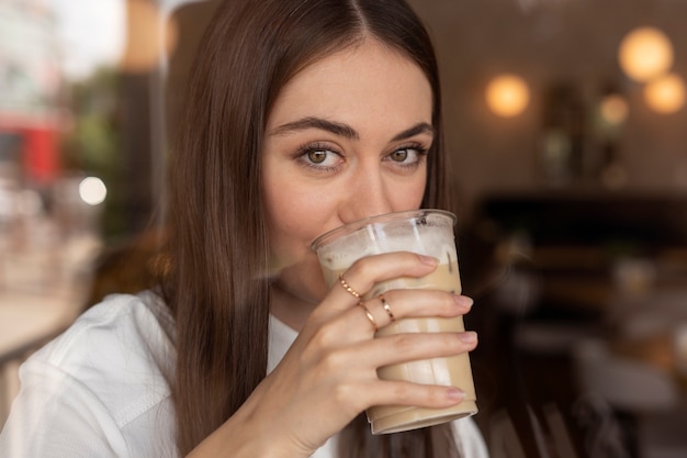 Foto gratuita giovane donna che beve caffè freddo