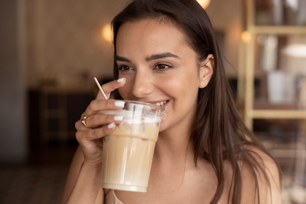 Foto gratuita giovane donna che beve caffè freddo