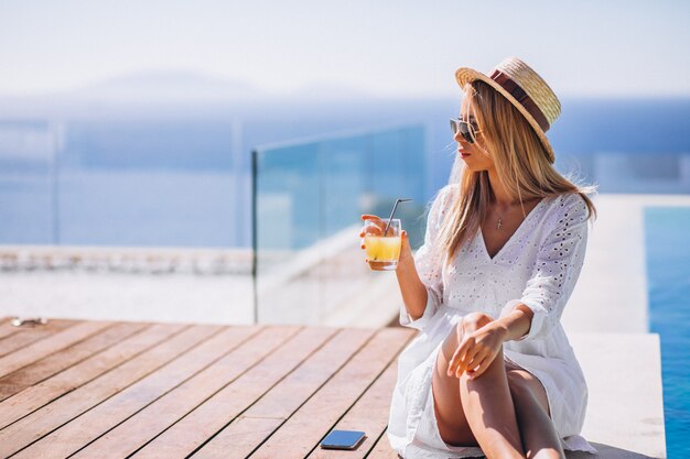 Young woman drinking juice bu the pool