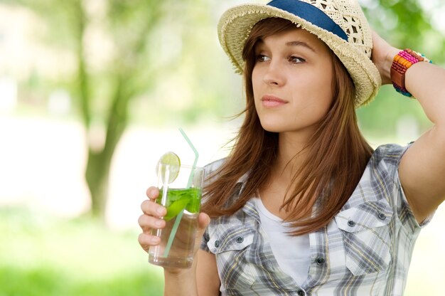 Молодая женщина пьет мохито