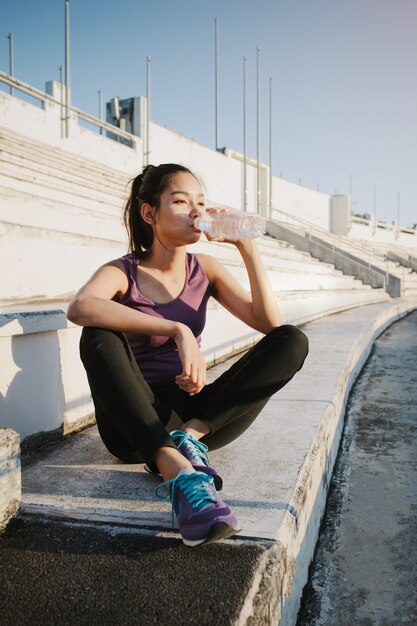 Young woman drinking water after exercising