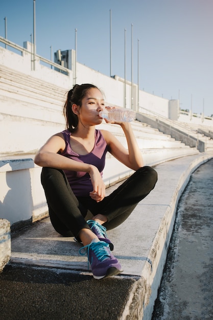 Young woman drinking water after exercising