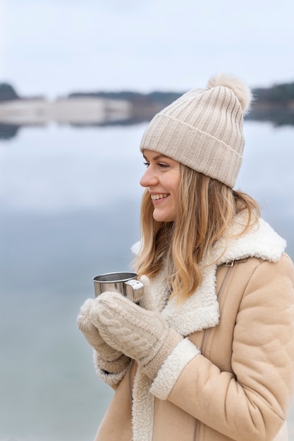 旅行中に湖のほとりで水を飲む若い女性