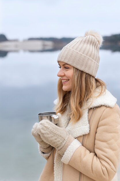 Young woman drinking water by the lake while traveling