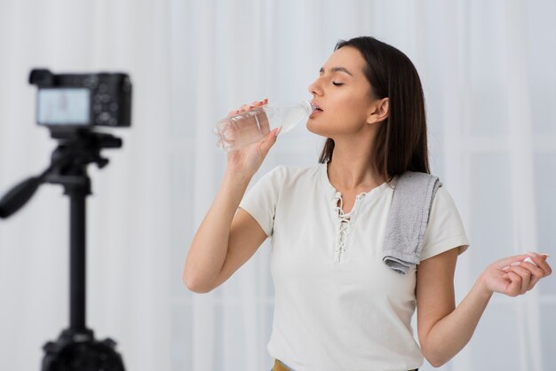 Young woman drinking water on camera