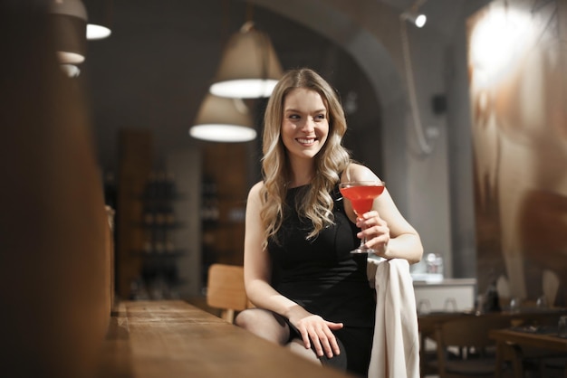молодая женщина выпивает коктейль в баре