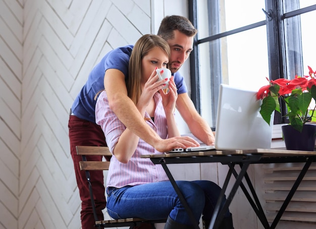 젊은 여성이 커피를 마시고 노트북으로 일하는 남자.